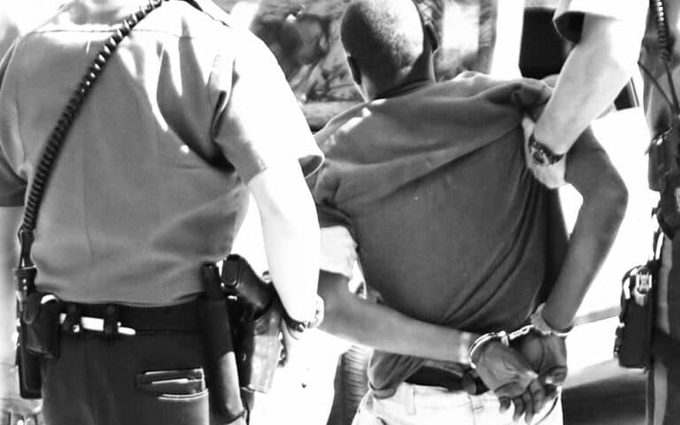 Policemen holding arrested man in handcuffs