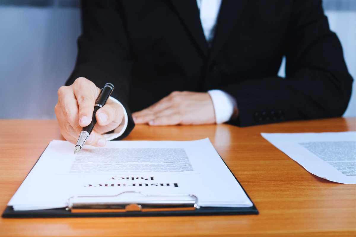 man in a suit pointing to an insurance policy document on a desk, symbolizing the importance of evidence and legal paperwork in San Diego personal injury claims.