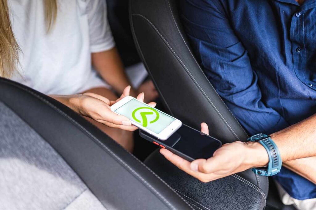 Passengers sharing rideshare trip details on their phones inside a car, illustrating how to save ride information and report an Uber or Lyft accident in San Diego.